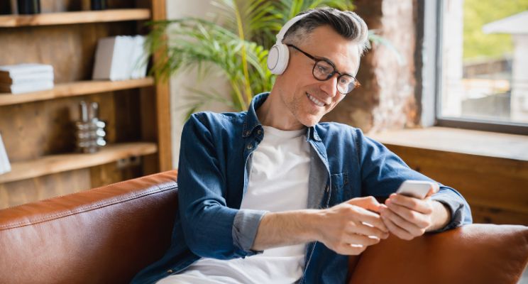 smiling man with headphones on looking at smart phone